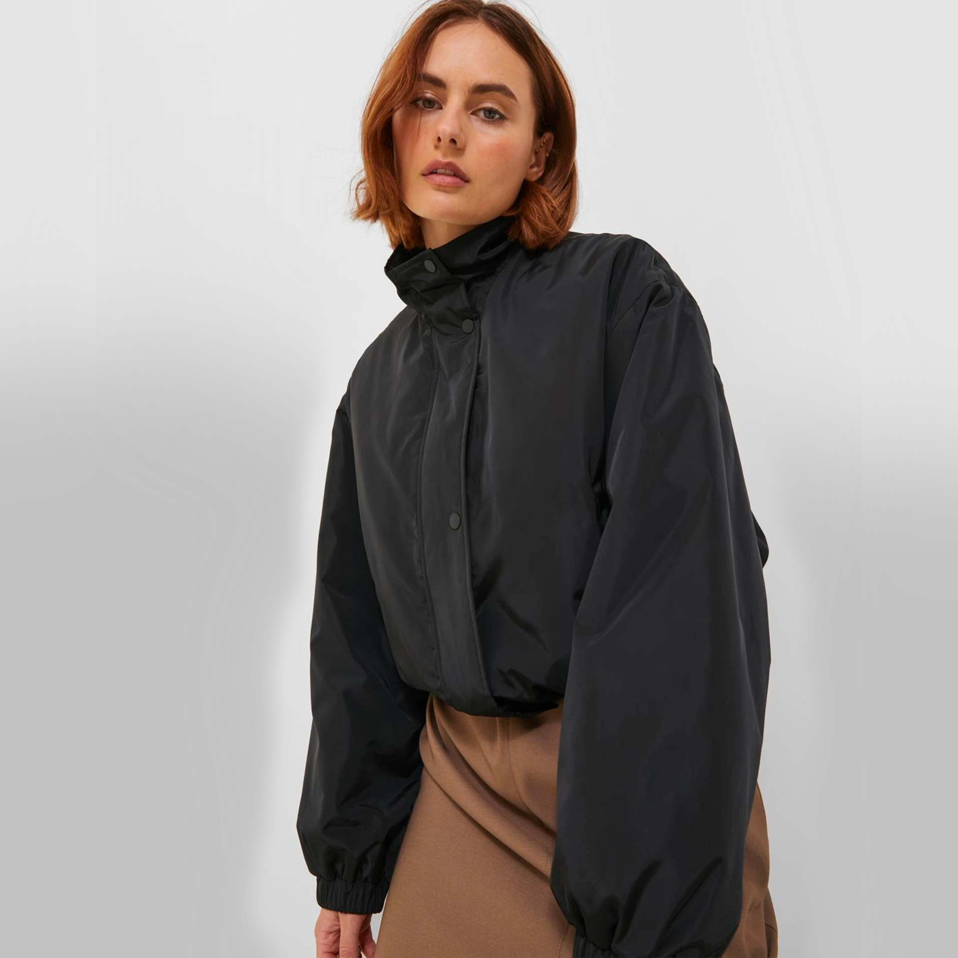 Casaco preto com gola alta e mangas largas usado por modelo