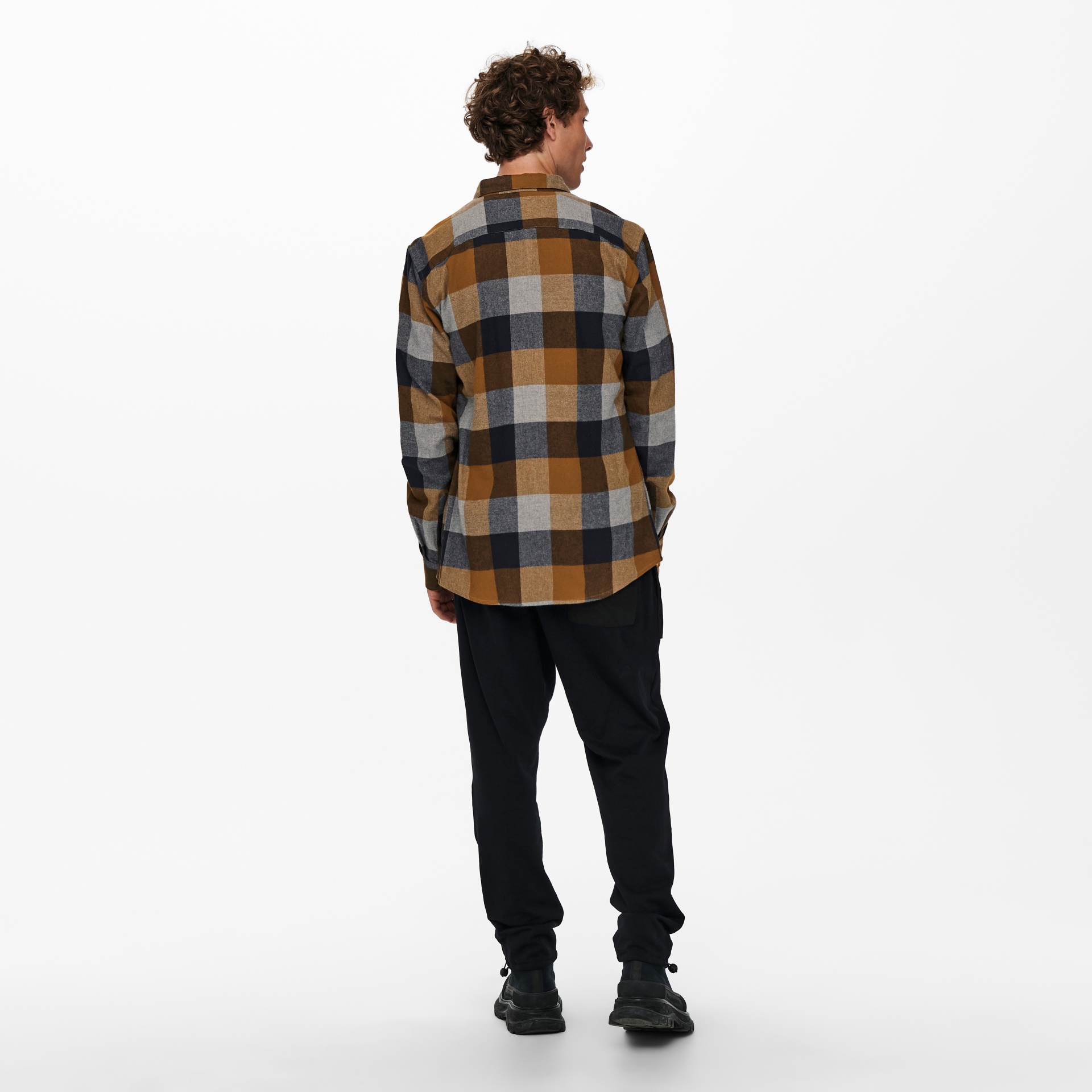 Homem de costas com camisa às riscas castanho e cinzenta, calças e sapatos pretos