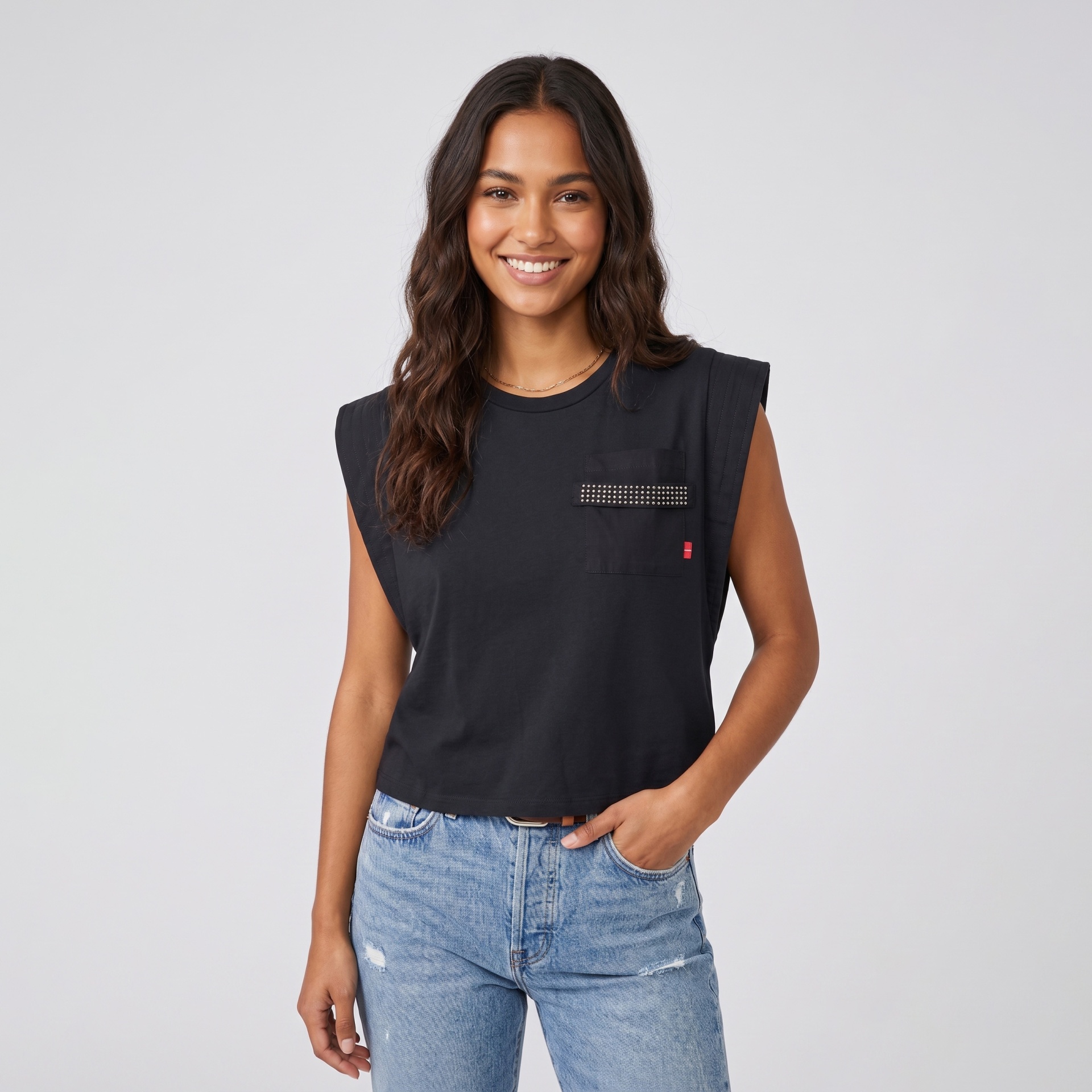 T-shirt preta com ombreiras e bolso decorado com tachas usada por mulher com calças de ganga azul claro