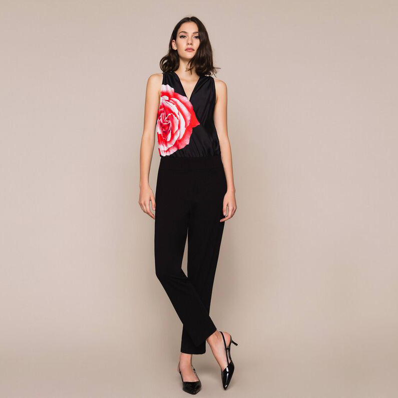 Macacão feminino preto com detalhe de flor vermelha e rosa e sapatos pretos de salto