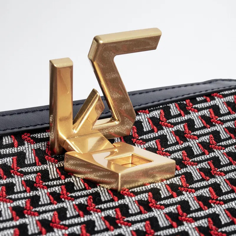 Fecho dourado metálico e tecido com padrão geométrico vermelho, preto e branco