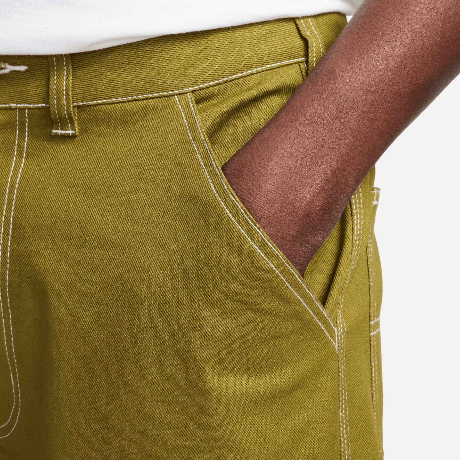 Calças verdes com costura branca e mão dentro do bolso