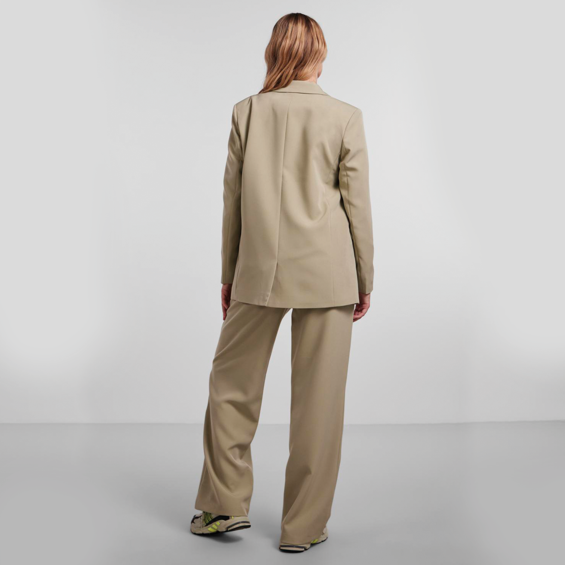 Conjunto de fato de senhora bege com blazer e calças largas visto de costas