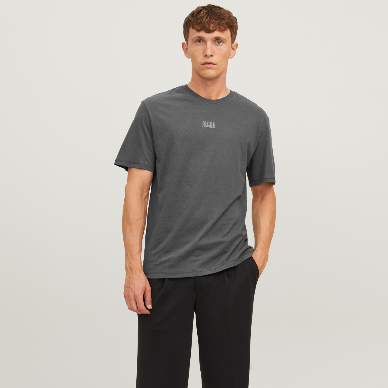 Homem a usar camiseta cinza escuro com texto JACK JONES e calças pretas