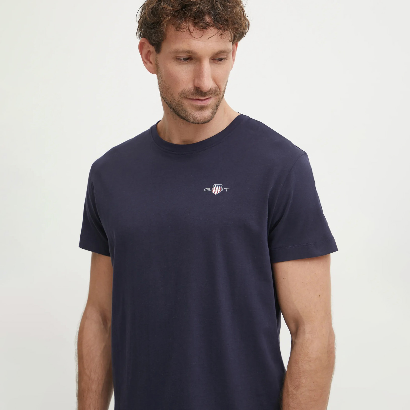 Homem de camiseta azul escura com pequeno logótipo GANT no peito