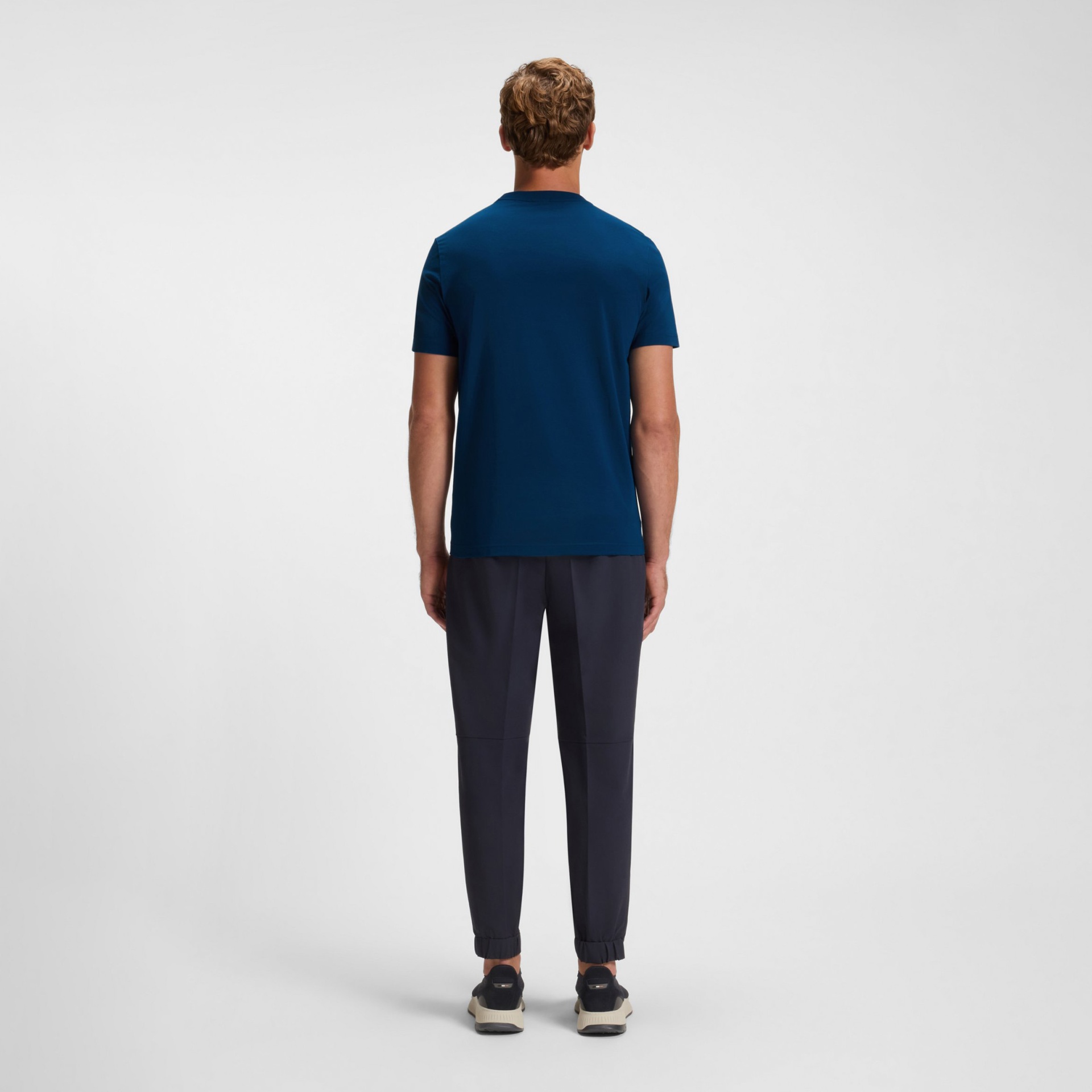 Homem com t-shirt azul e calças azul escuro visto de costas