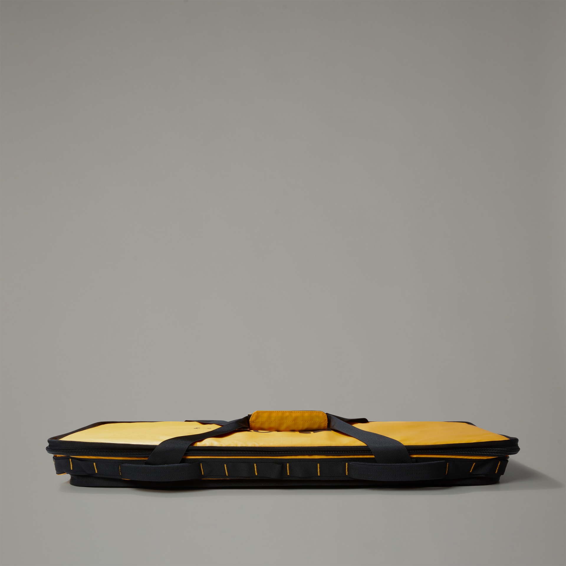 Mala de transporte amarela e preta com alças sobre fundo cinza