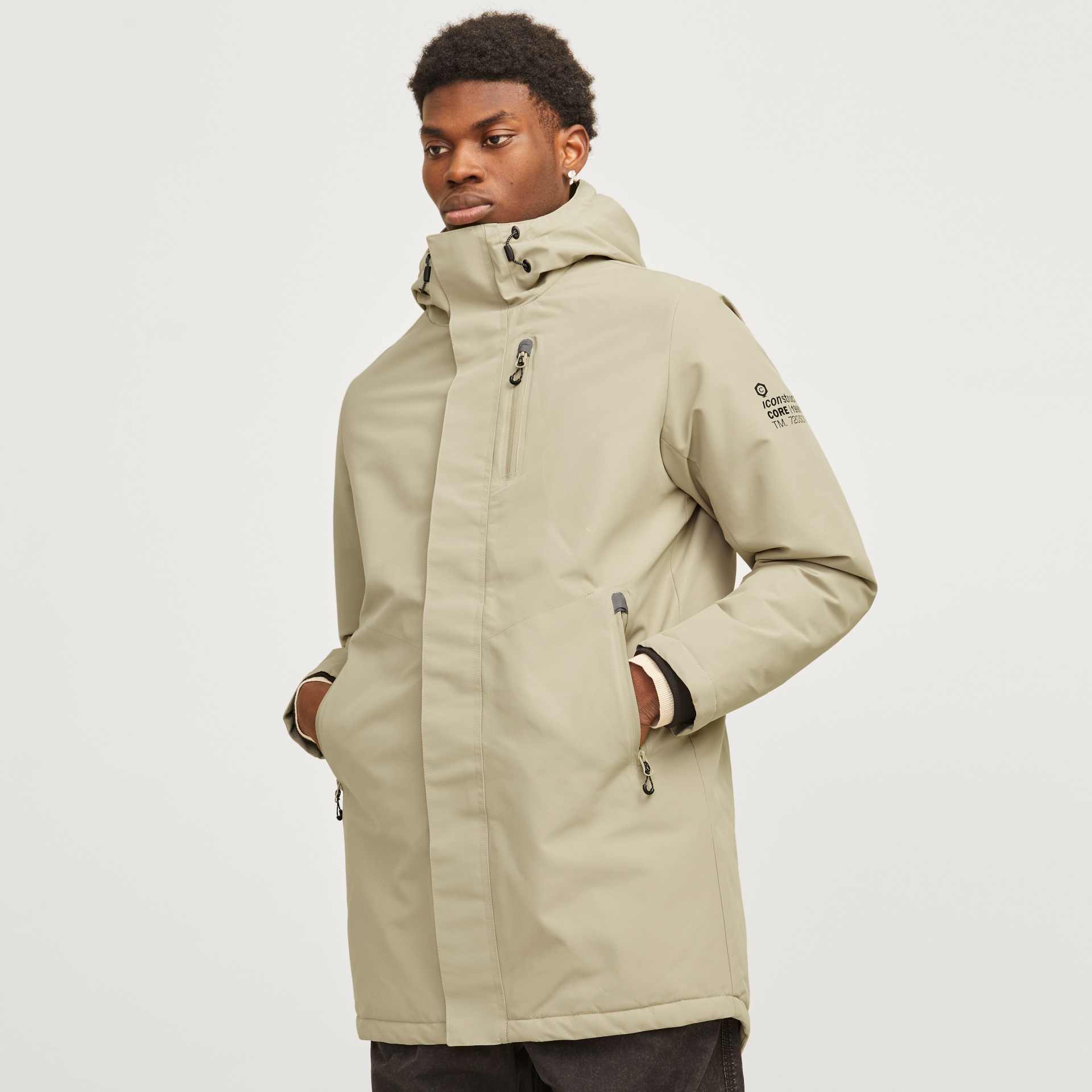 Casaco bege claro com capuz e bolsos, modelo masculino com texto na manga