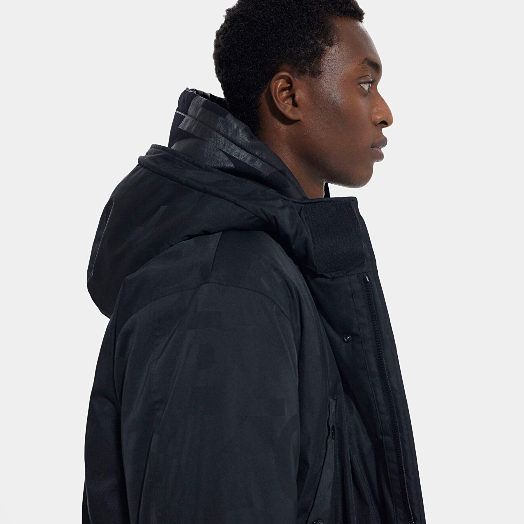 Casaco impermeável preto com capuz largo visto de lado