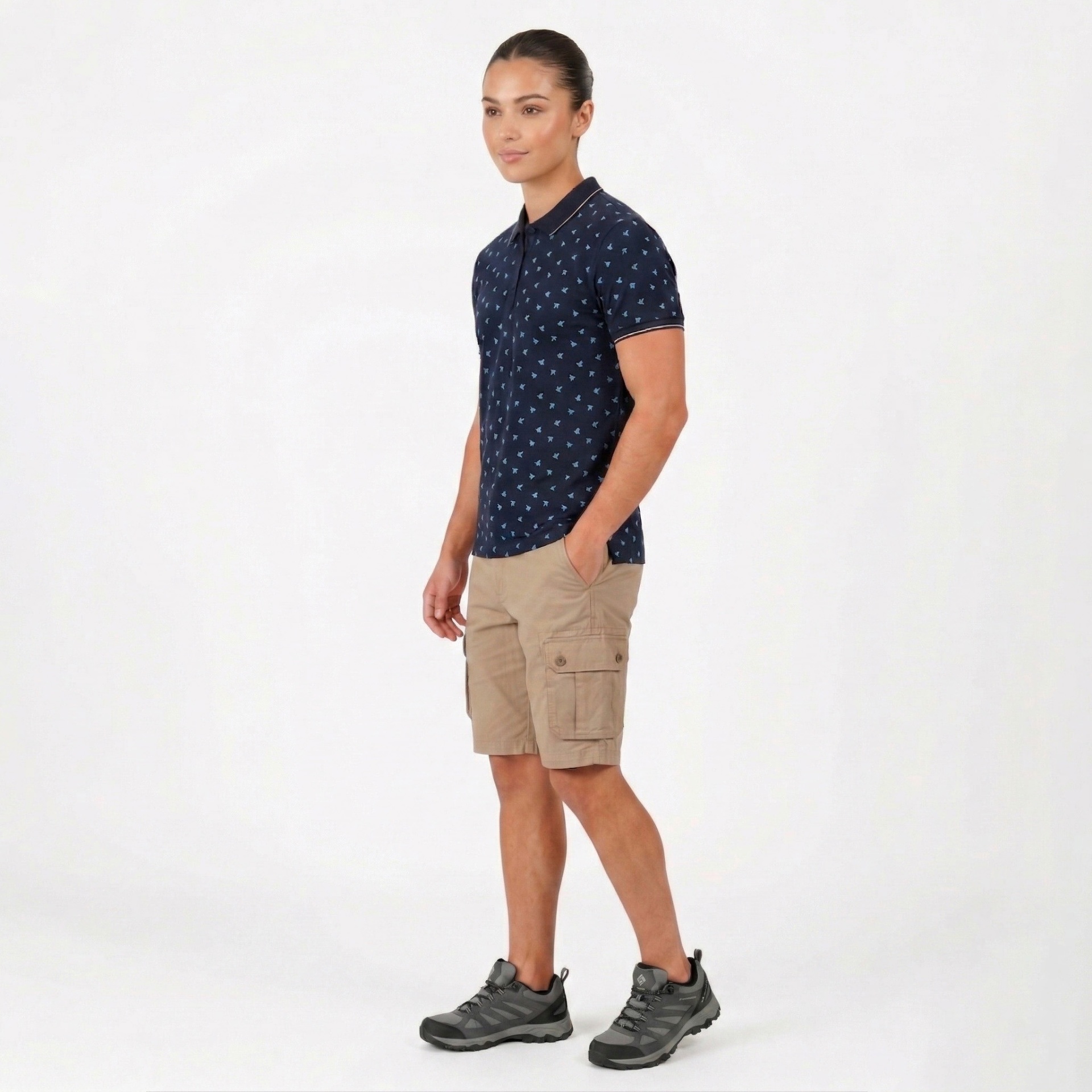 Homem com polo azul escuro estampado, calções cargo bege e sapatos cinza.