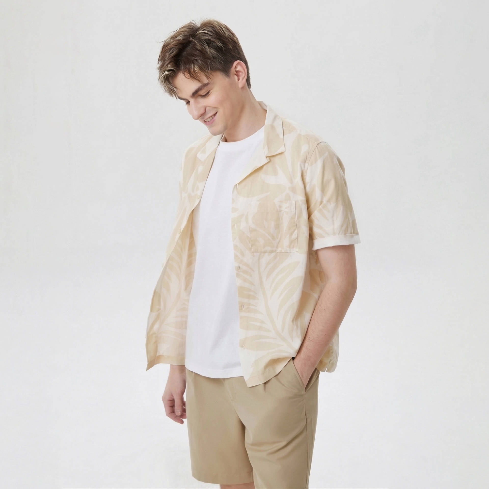 Homem com camisa bege estampada, t-shirt branca e calções bege