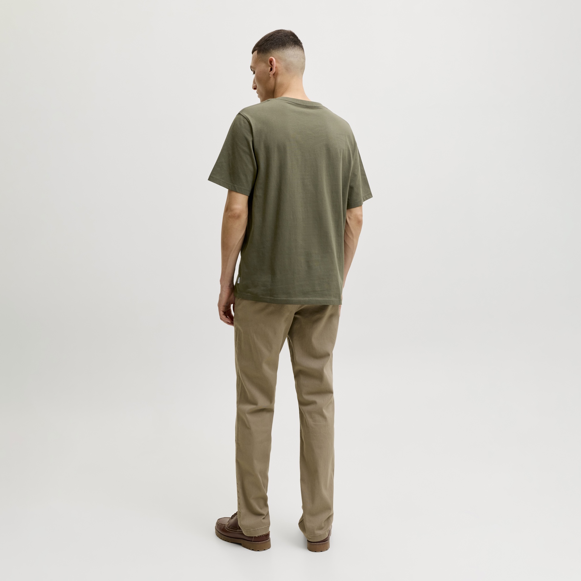 Homem visto de costas com t-shirt verde-oliva e calças bege