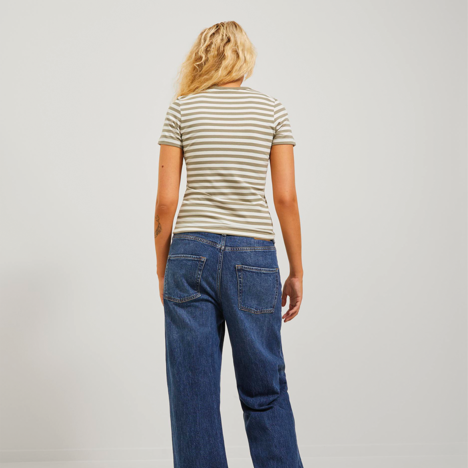 Mulher de costas com camisola listrada e calças de ganga azul