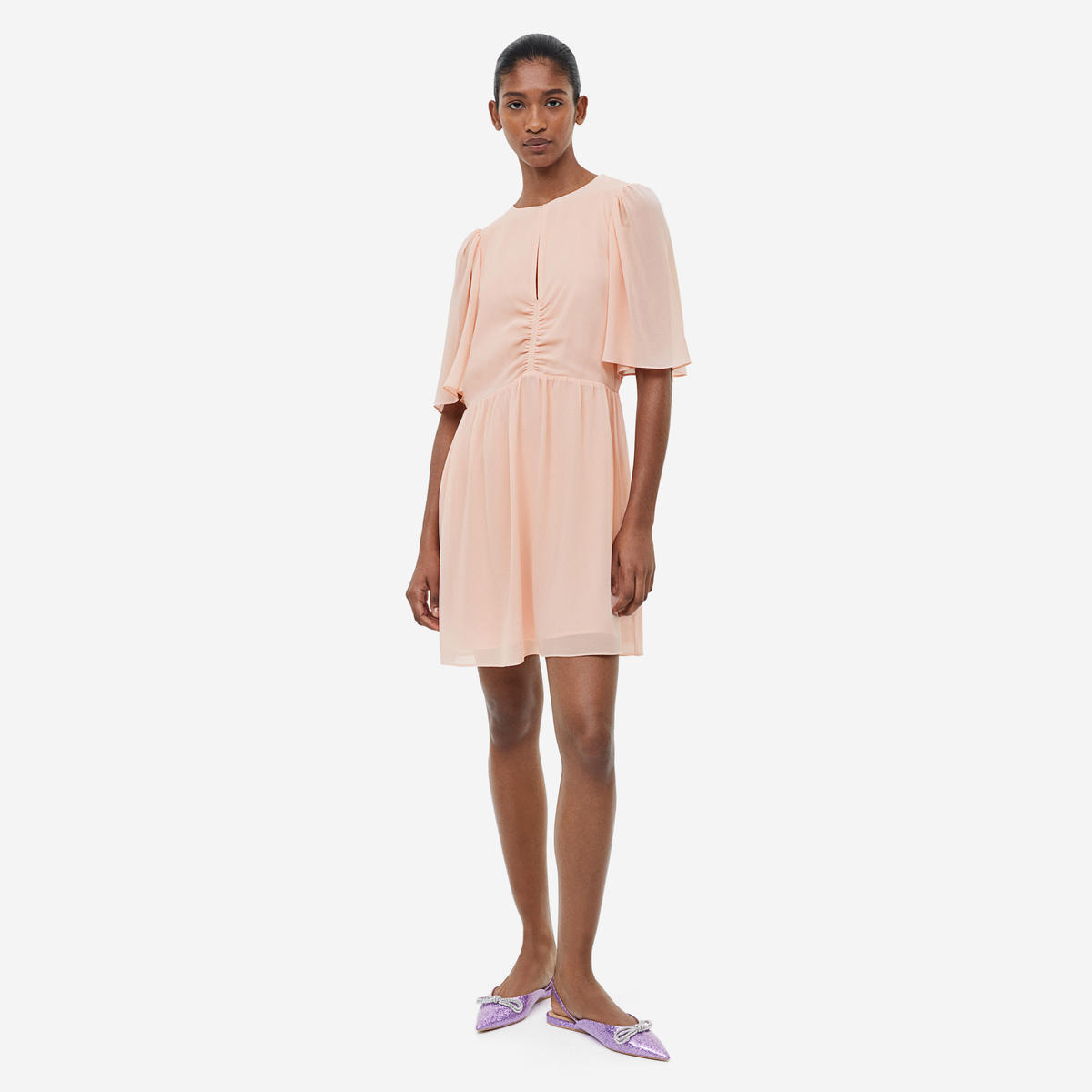 Mulher vestindo vestido cor salmão e sapatos lilás com brilho