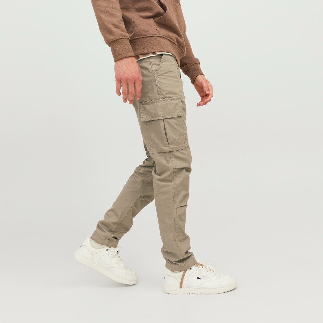 Homem vestindo calças cargo bege e ténis brancos