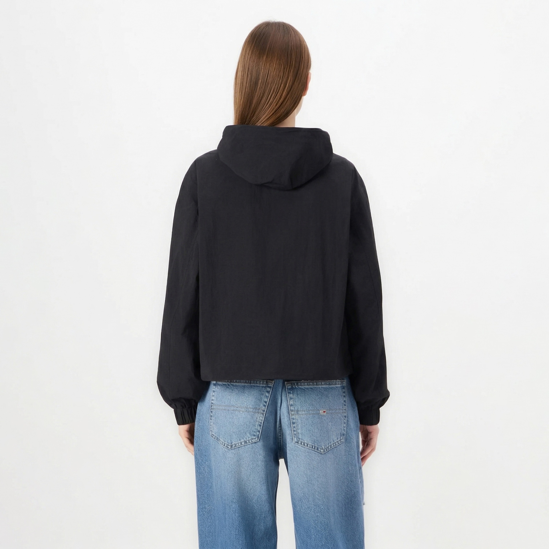 Pessoa de costas com casaco preto e calças de ganga azuis