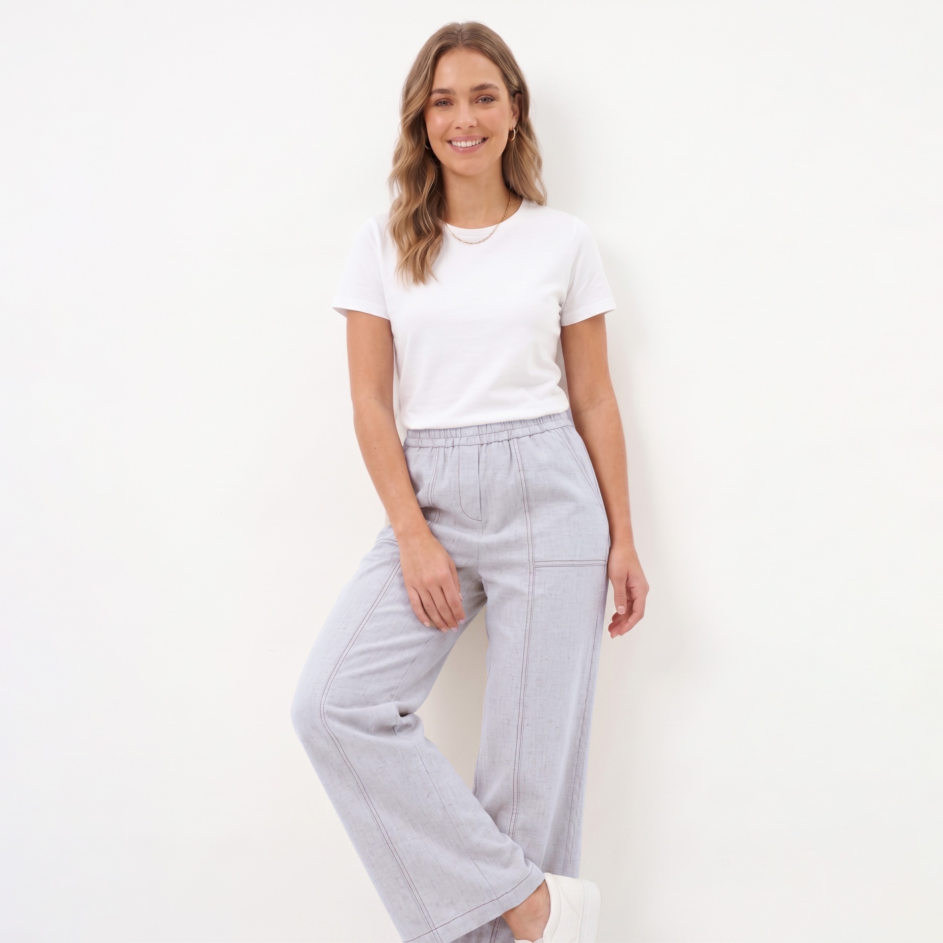 Mulher com t-shirt branca e calças cinzentas claras