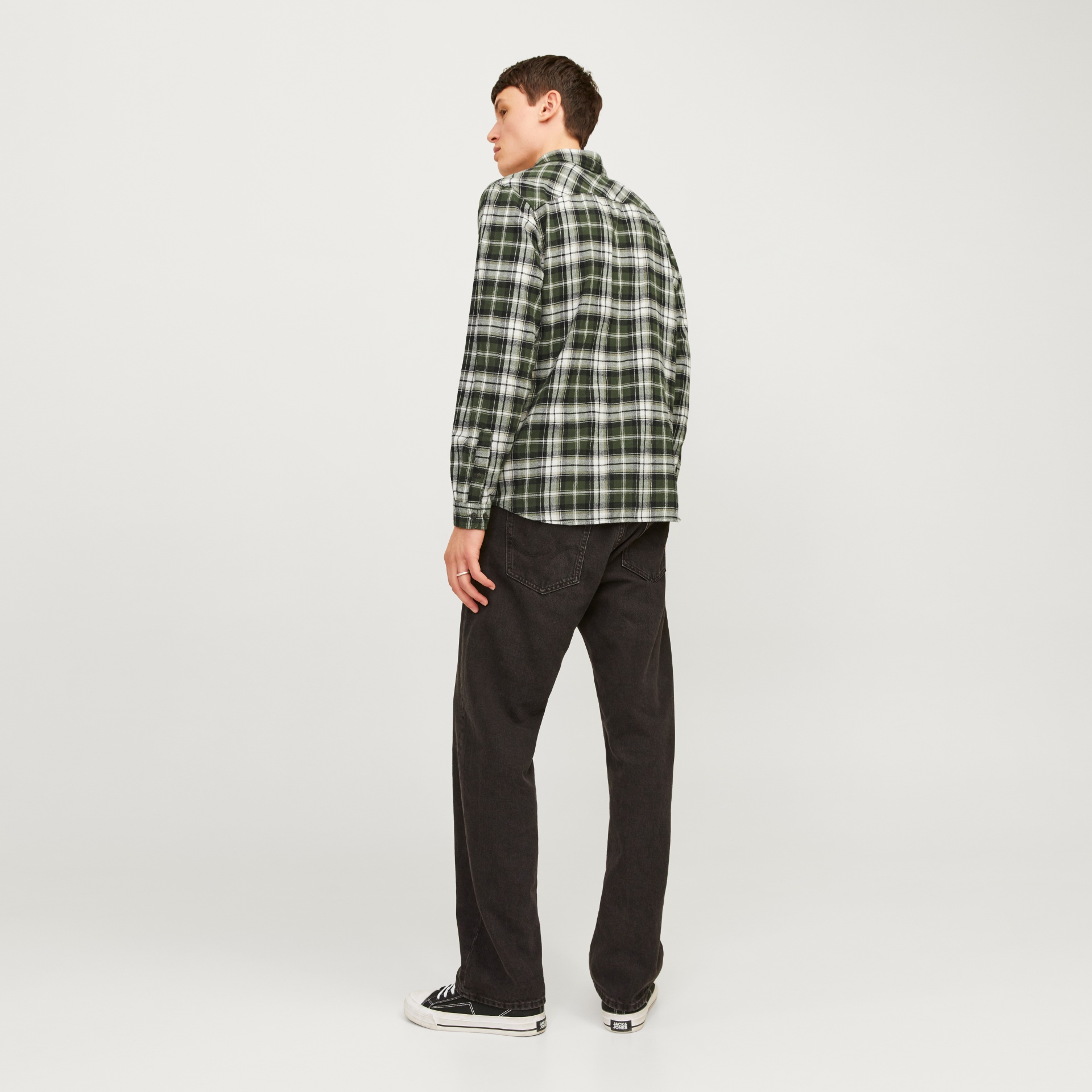 Homem de costas com camisa xadrez verde e calças pretas