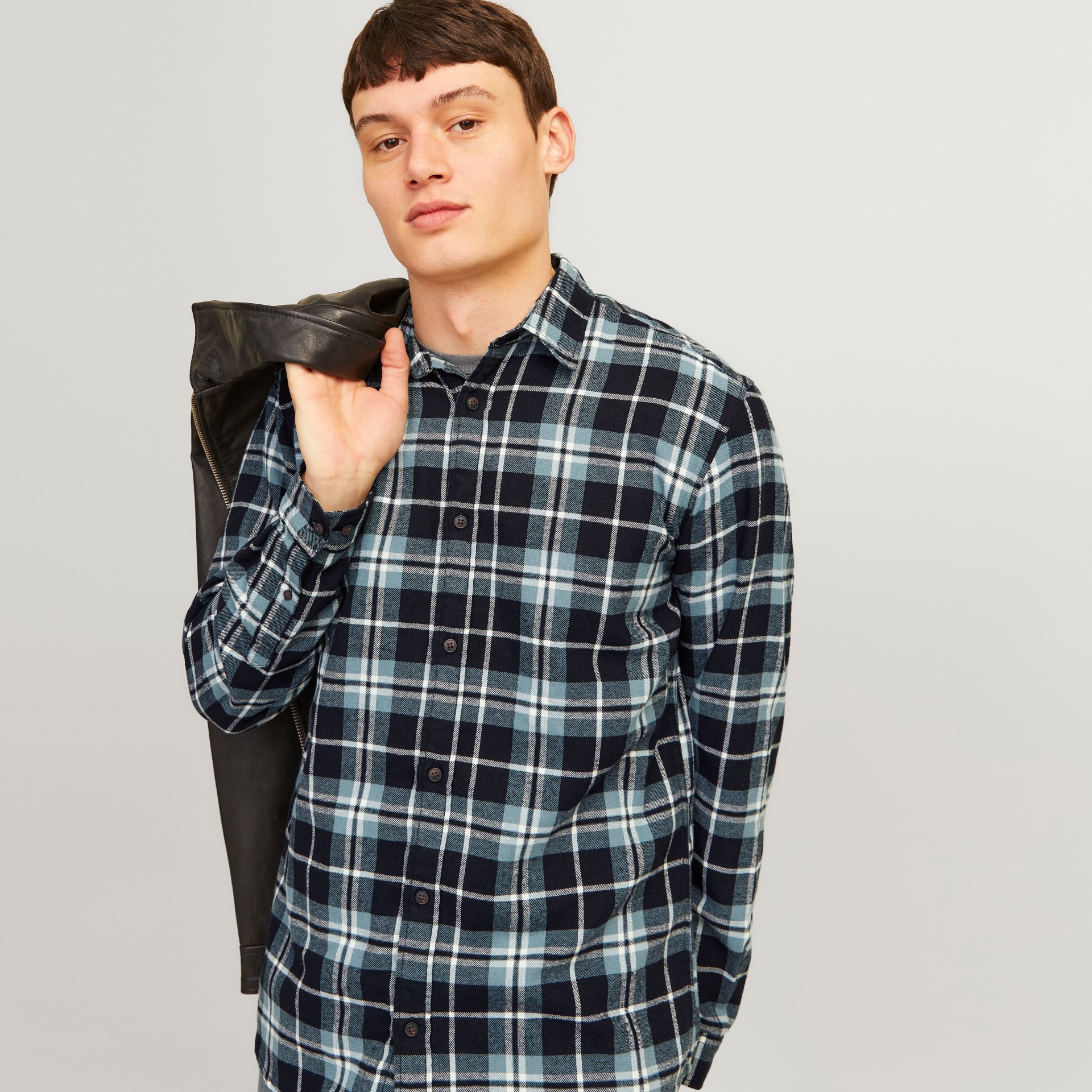 Camisa xadrez azul, preto e branco com botões e casaco de couro preto no ombro