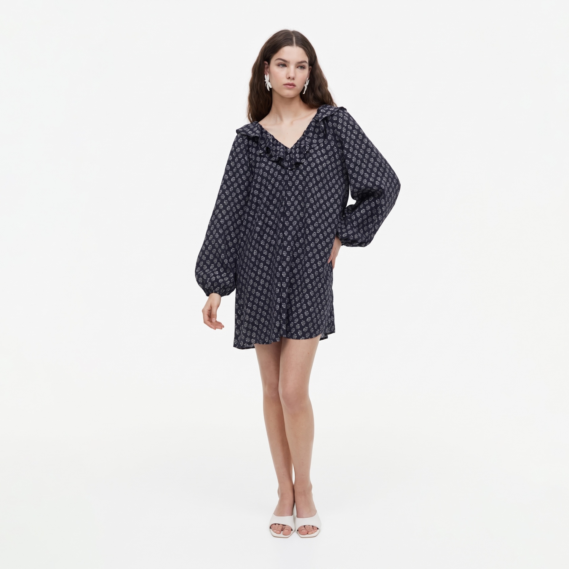 Mulher com vestido curto azul escuro florido e brincos brancos
