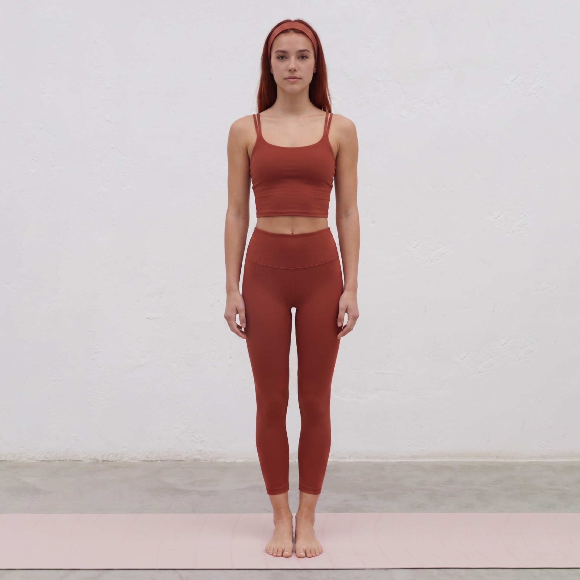 Mulher veste conjunto desportivo castanho alaranjado de top e leggings em tapete rosa