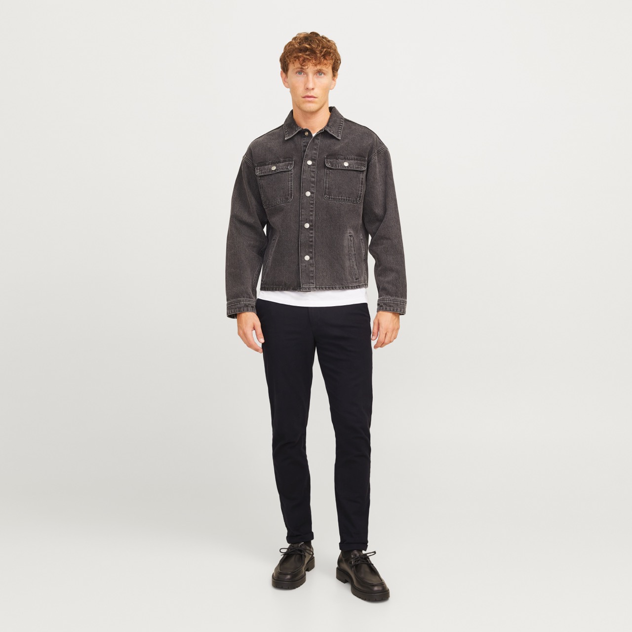 Modelo a usar casaco denim negro com botões, calças pretas e sapatos pretos