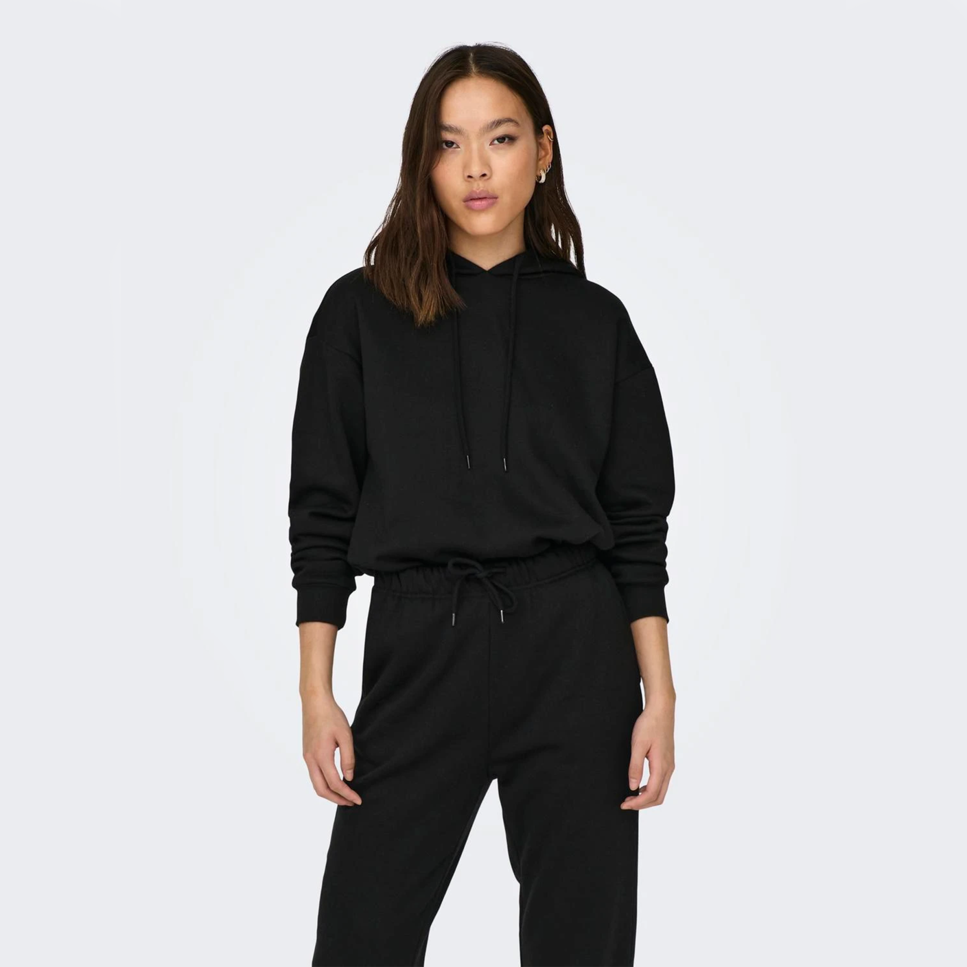 Mulher com conjunto desportivo preto de hoodie com capuz e calças pretas