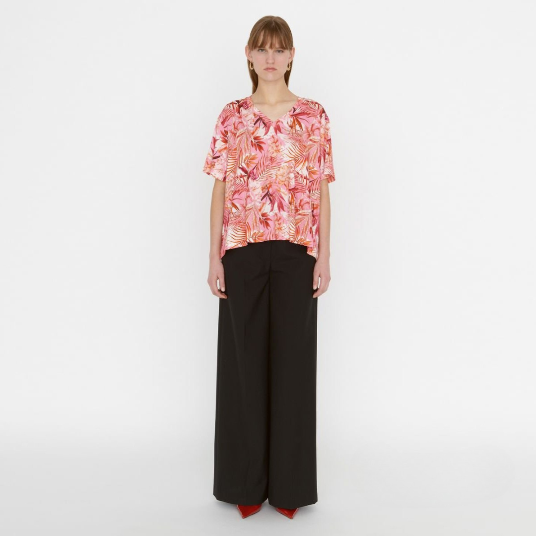 Modelo com blusa floral rosa e laranja e calças pretas largas