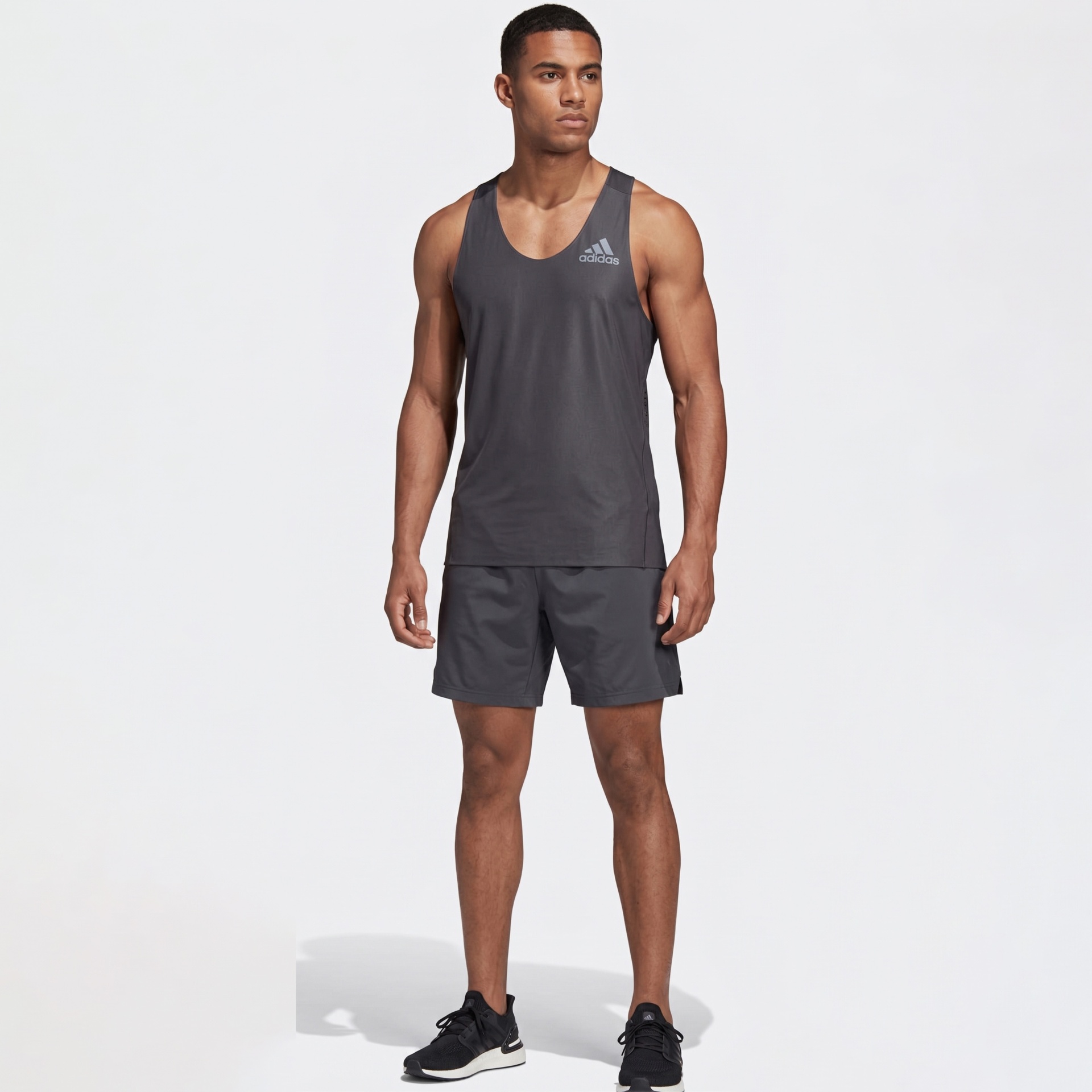 Homem com roupa desportiva preta da adidas em fundo branco.