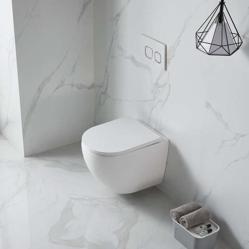 Sanita suspensa branca com botão de descarga na parede e toalhas cinzentas enroladas ao lado