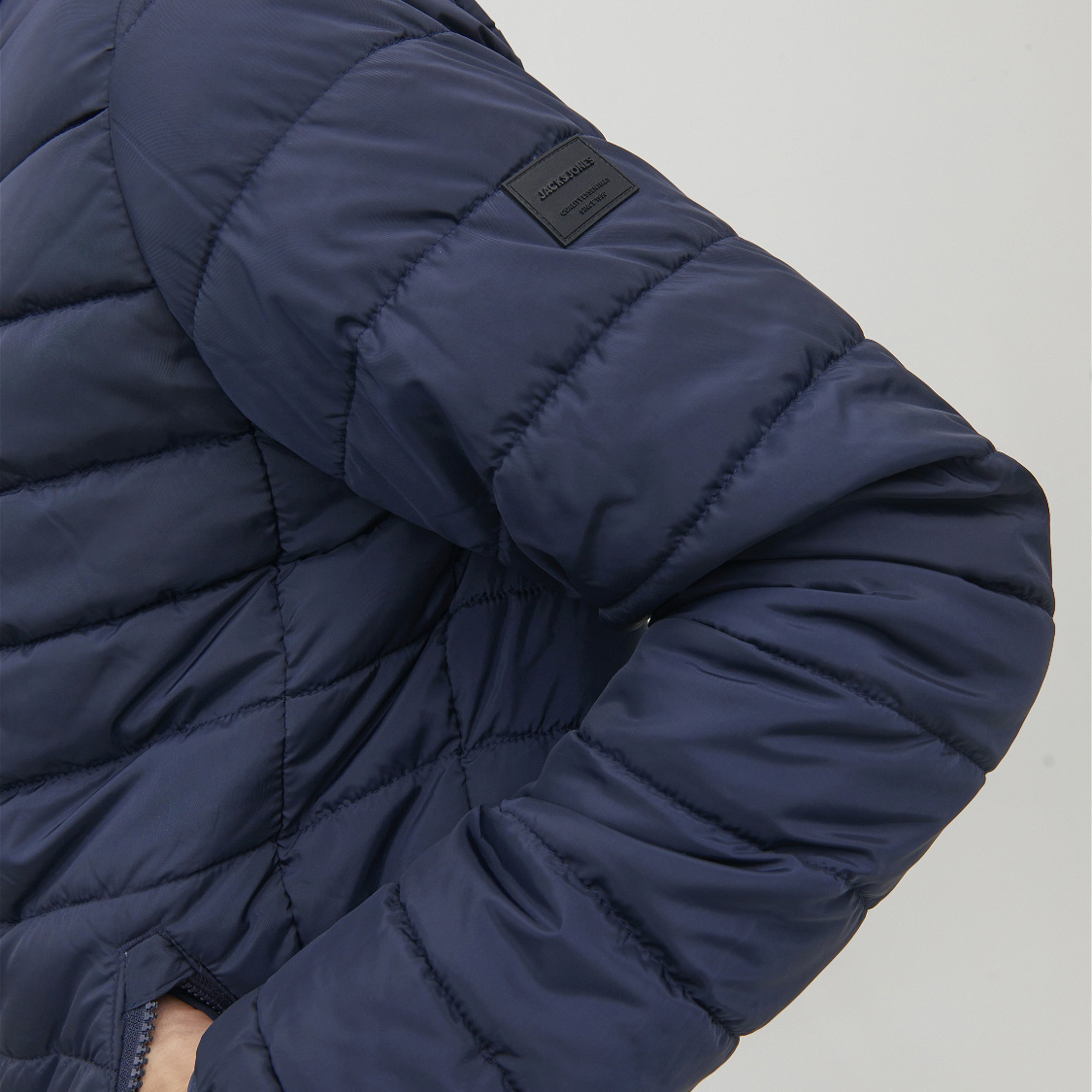 Casaco acolchoado azul escuro com etiqueta preta na manga