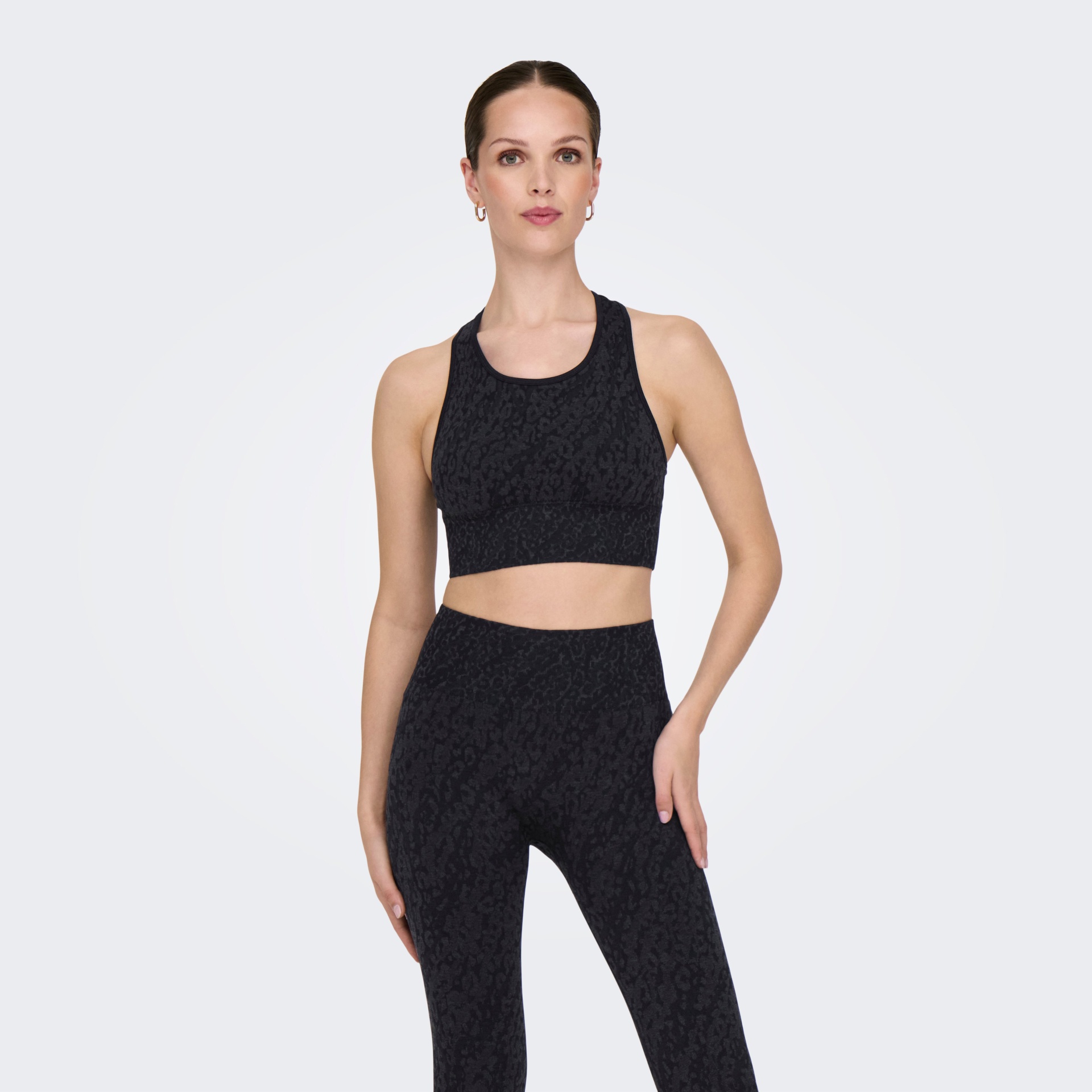 Conjunto desportivo feminino preto com padrão texturizado em fundo branco