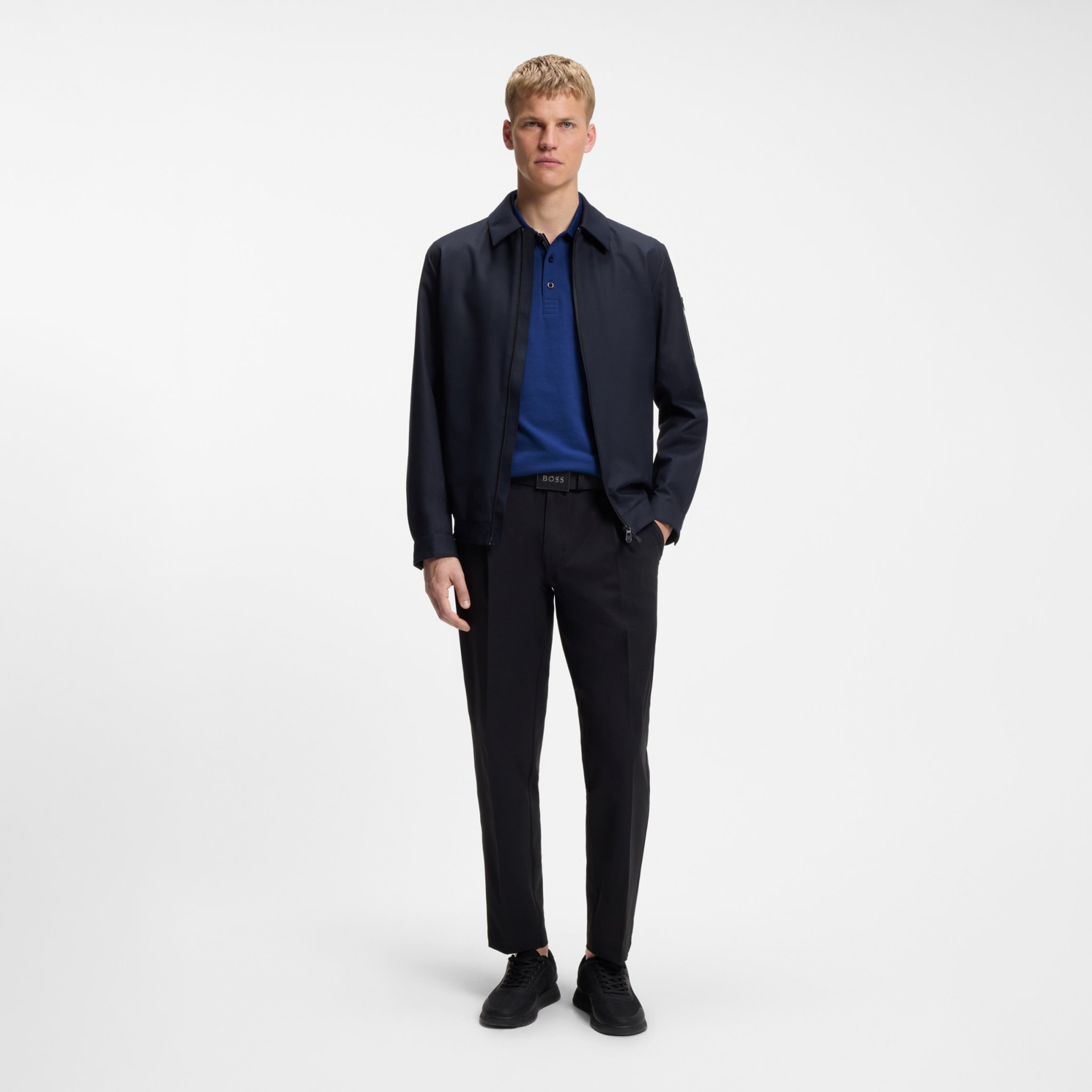 Homem magro com roupa azul e preta em fundo branco