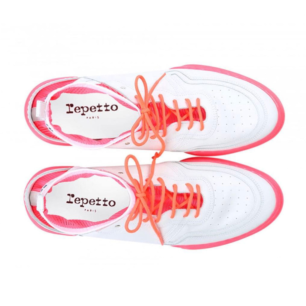 Ténis brancos com sola rosa e atacadores laranja com a marca Repetto Paris na palmilha