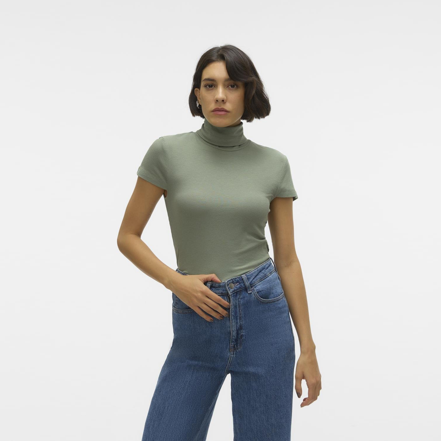 mulher com camisola verde clara de gola alta e calças de ganga azuis