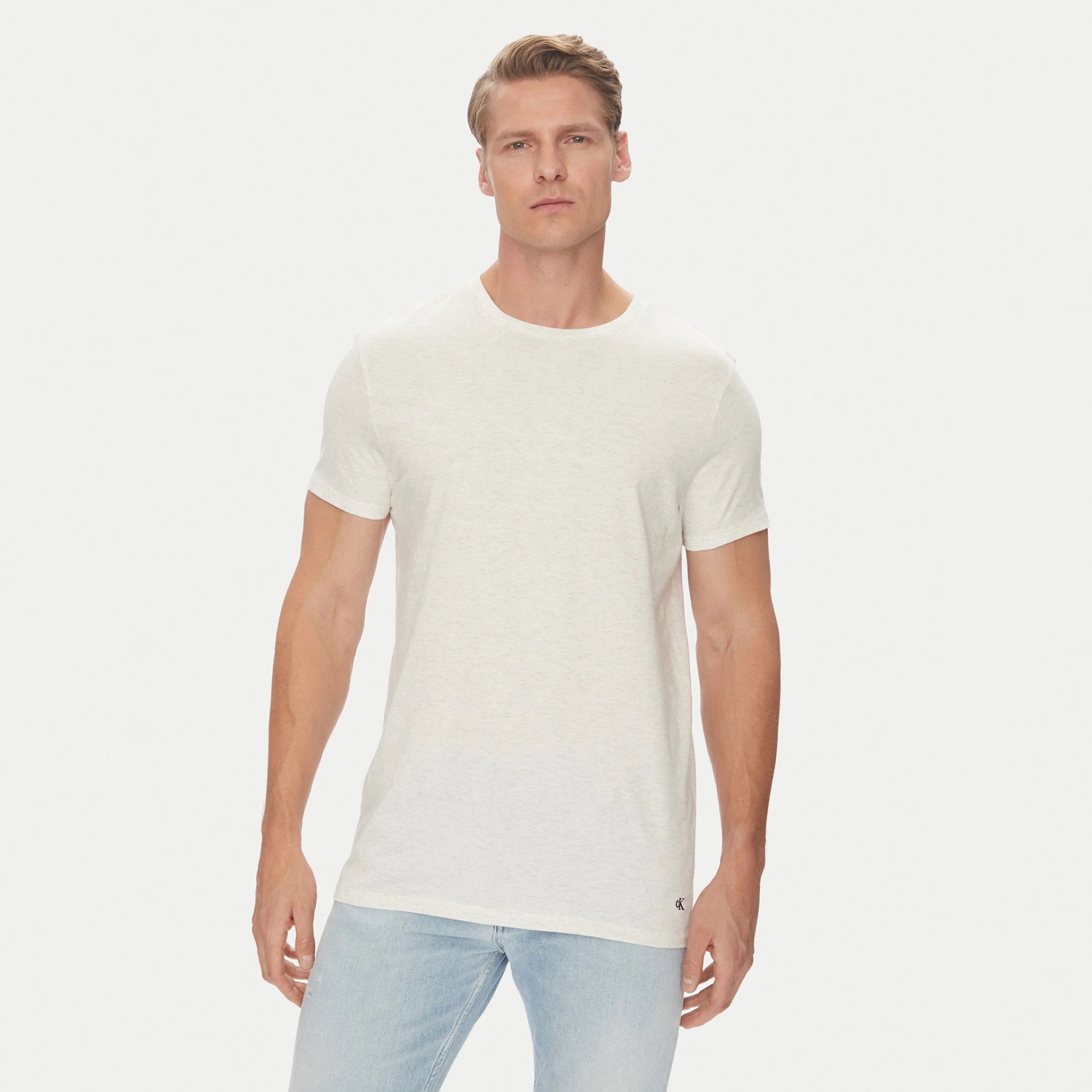 Homem com t-shirt branca e calças de ganga azul clara com fundo branco