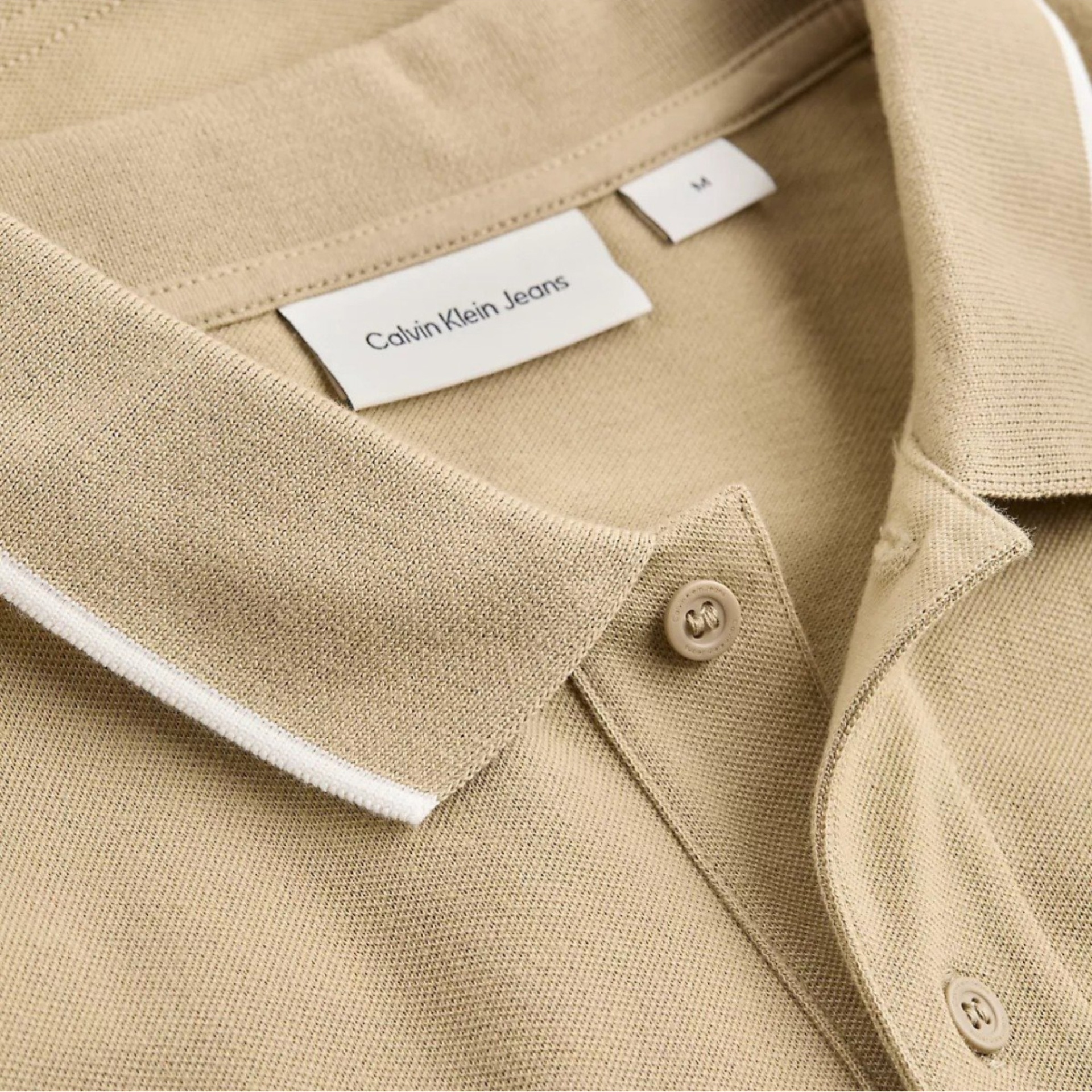 Polo bege Calvin Klein Jeans com gola com detalhe branco e botões.