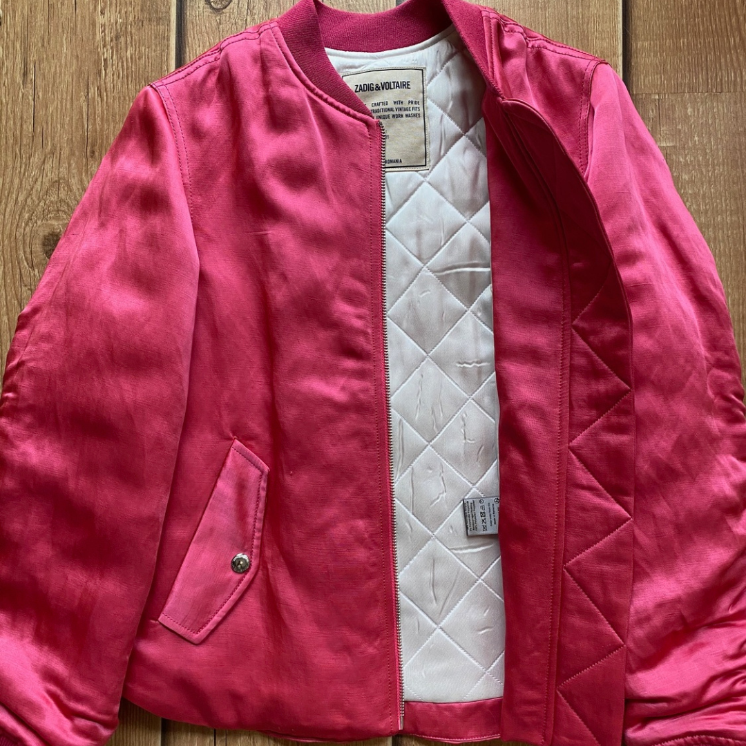 Casaco rosa aberto mostrando forro acolchoado creme com etiqueta Zara Woman em chão de madeira