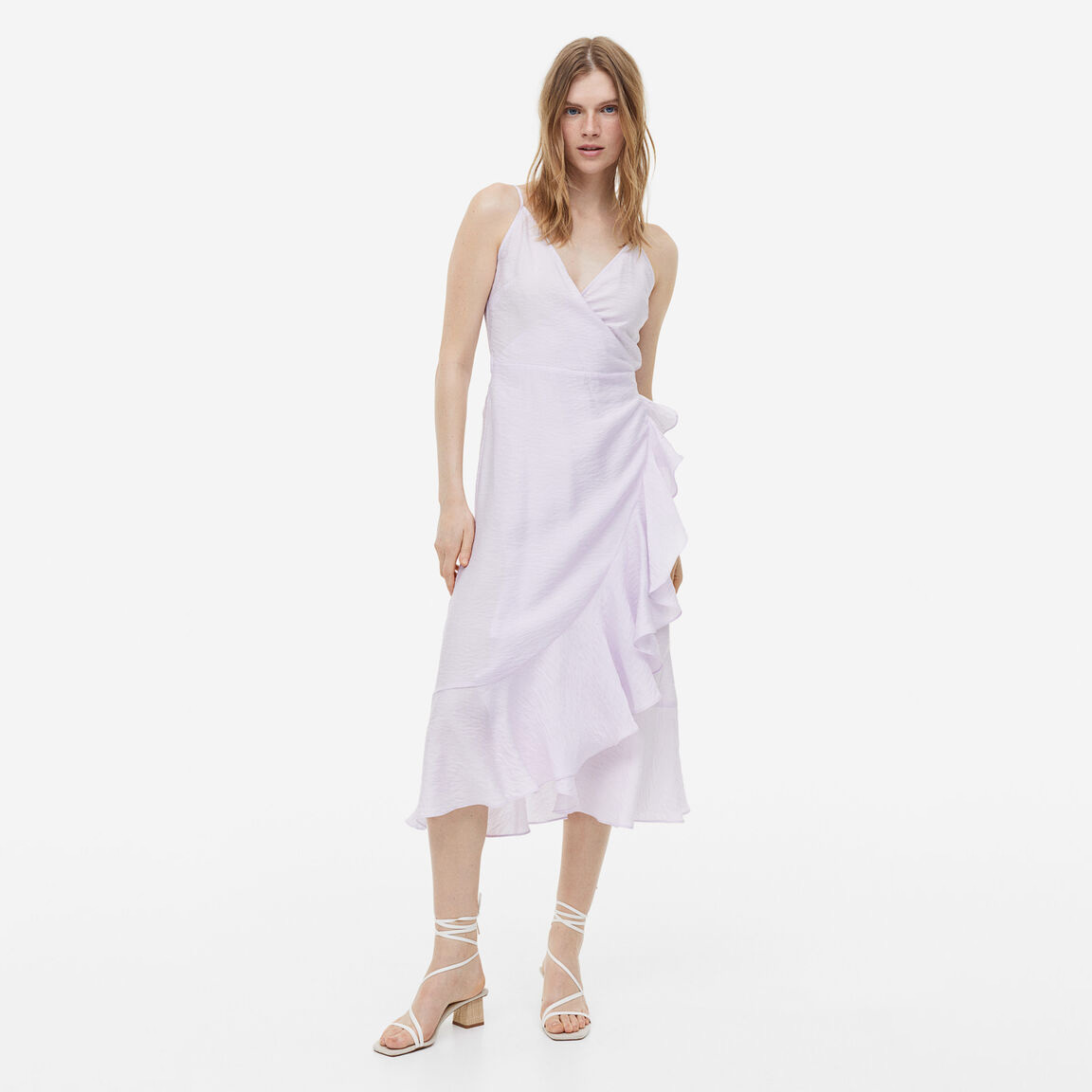 Vestido midi lilás claro com folhos e sandálias brancas.