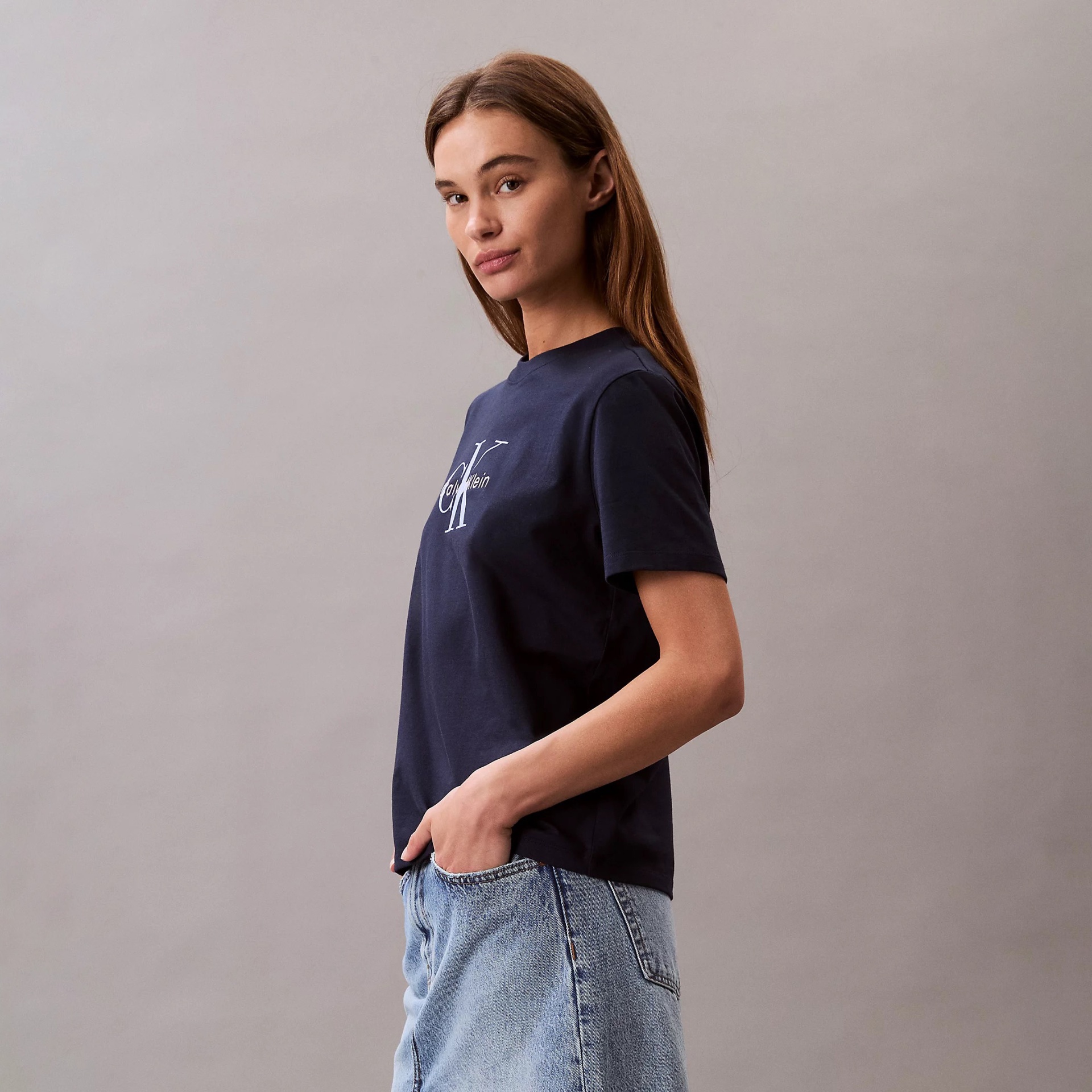T-shirt azul Calvin Klein com logótipo branco, usada por mulher com saia de ganga