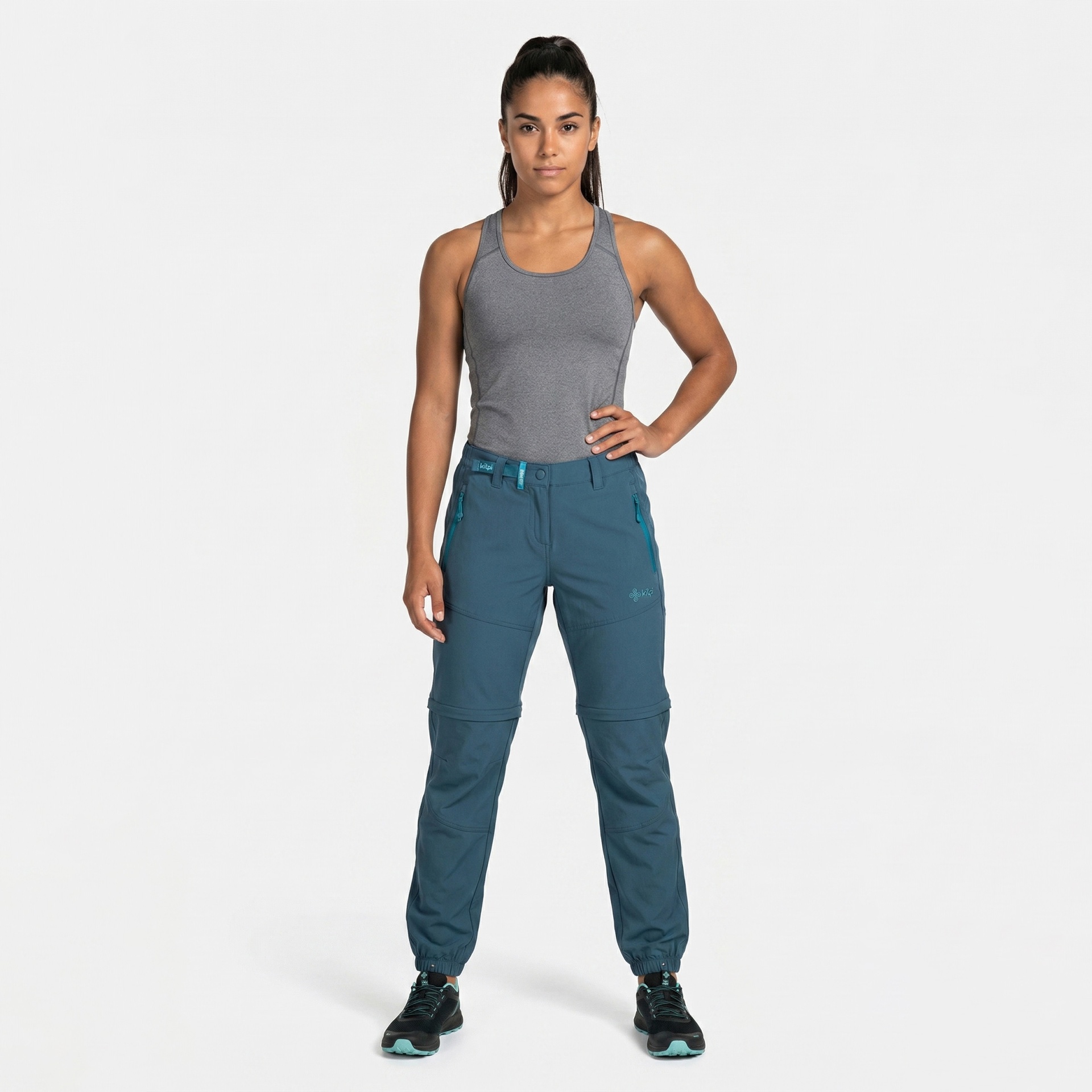 Mulher vestindo calças desportivas azuis e t-shirt cinza em fundo branco