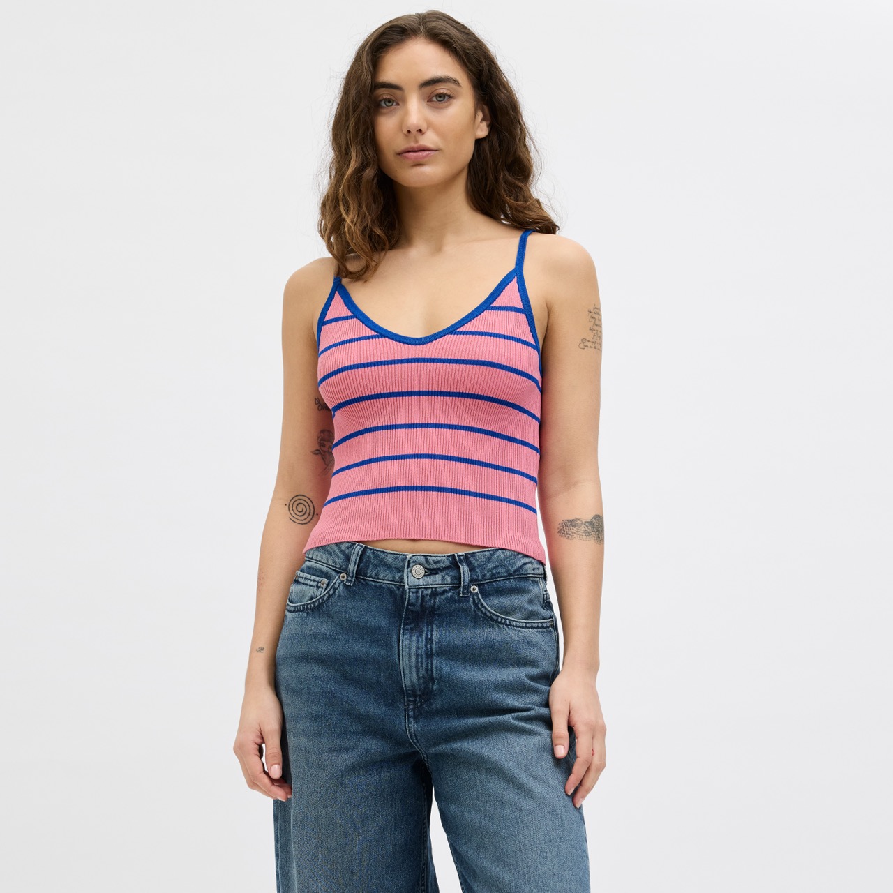 Top rosa com riscas azuis usado por mulher com jeans