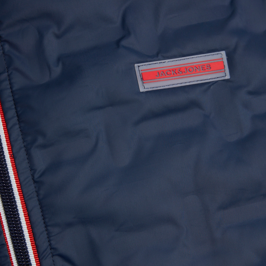 Tecido azul escuro com etiqueta JACK & JONES e faixa lateral com riscas branca, vermelha e azul