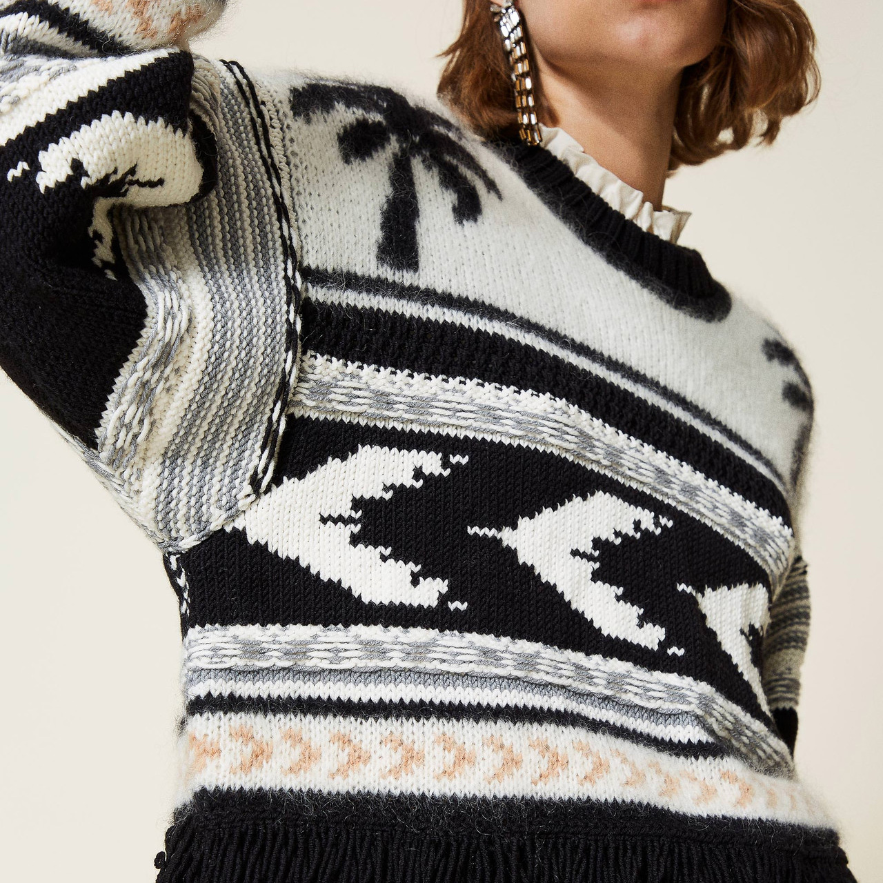 Camisola de malha preta e branca com padrão geométrico e franjas