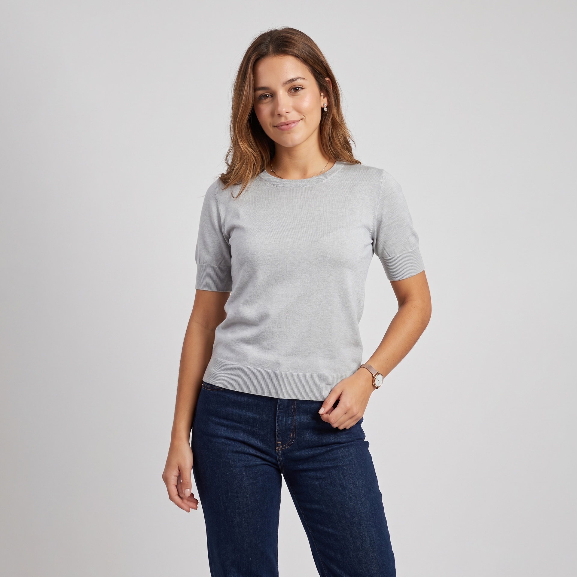 Camisola feminina cinzenta clara de manga curta com jeans azul escuro em fundo cinzento claro