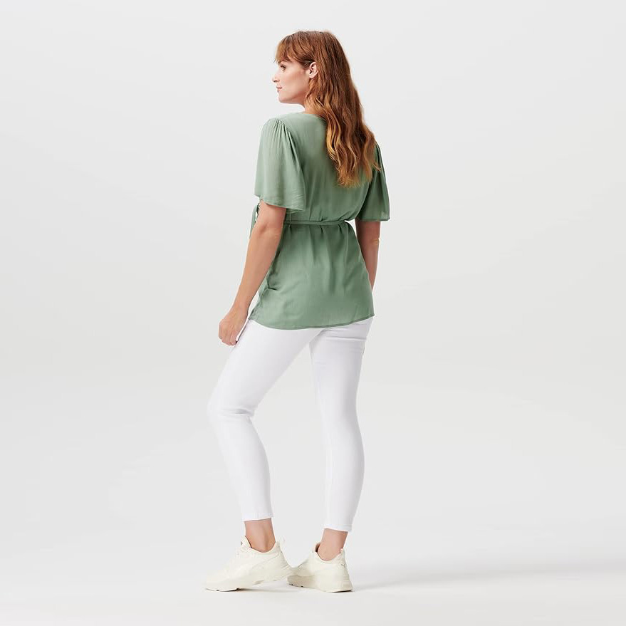 Mulher de costas com blusa verde e calças brancas