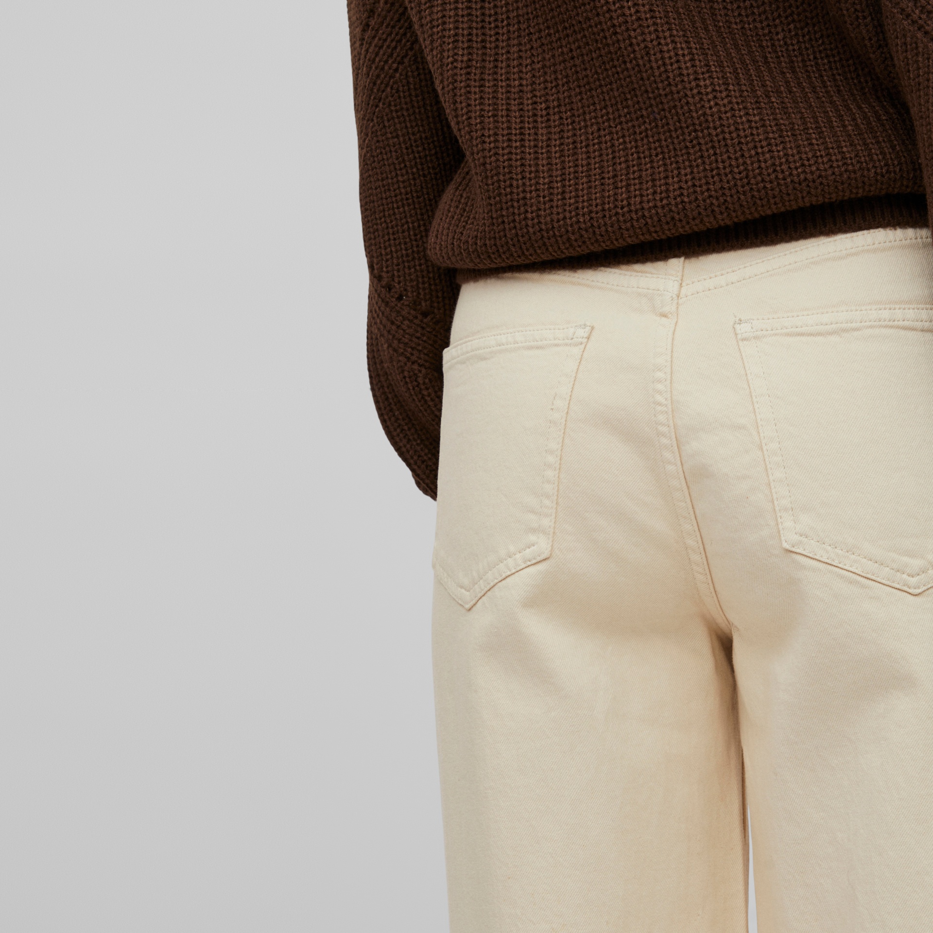 Calças bege com bolsos traseiros e camisa castanha de malha