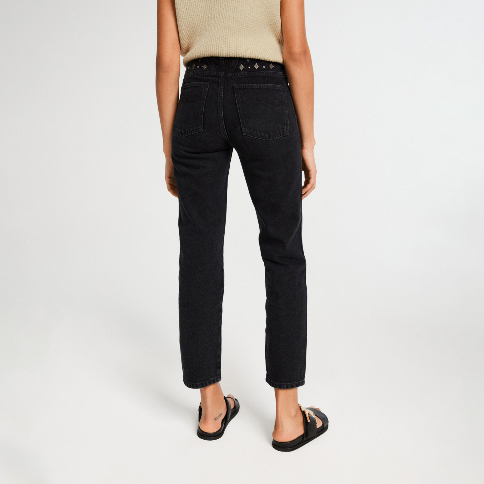 Calças de ganga pretas com decoração prateada na cintura vistas de costas