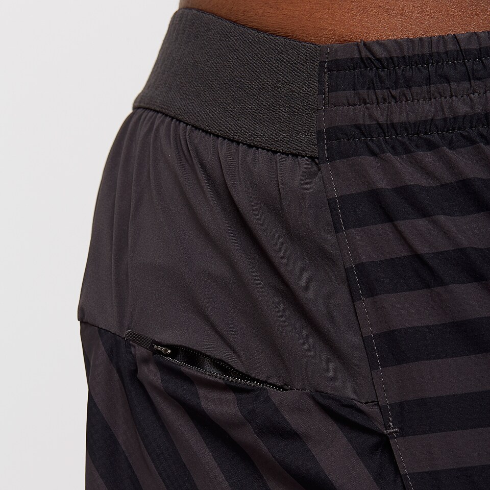 Calças desportivas pretas com riscas escuras e bolso com fecho.