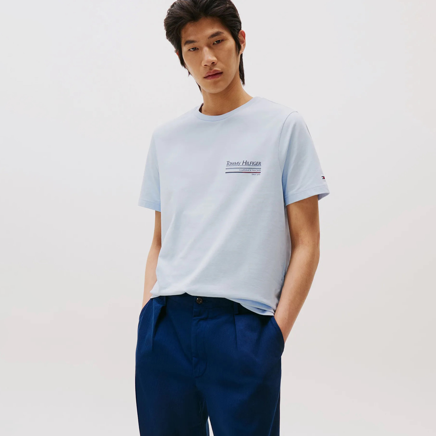 Homem com t-shirt azul clara Tommy Hilfiger e calças azul-escuras